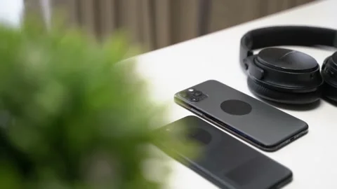 Close up video of two dark smartphone and headphones on a white table Video stock 163862308