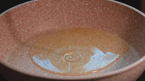 Close-up video of vegetable oil being poured into a non-stick frying pan Stock Footage 280830901