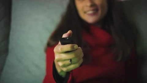 Close-up video of a woman’s hand using a TV remote to change channels at night.  Stock Footage 346322986