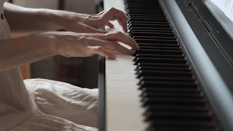 Close-up video of woman's hands playing the piano in pink dress Stock Footage 281572463