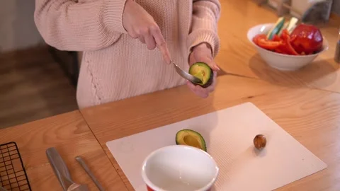 Close-up video of woman’s hands scooping an avocado during food preparation. Video stock 266453610