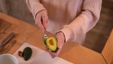 Close-up video of woman’s hands scooping an avocado during food preparation. Video stock 308767728