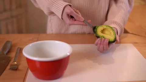 Close-up video of woman’s hands scooping an avocado during food preparation. Video stock 308774376