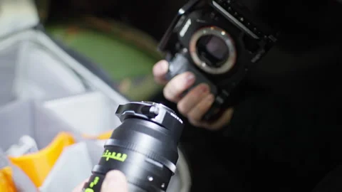 Close up video of a young man showing how to add a camera lense to a dslr Stock Footage 270281146