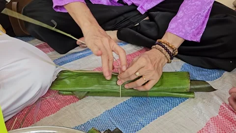 Close-up of a Vietnamese woman's hands wrapping traditional Banh Tet cake. Stock Footage 329817246