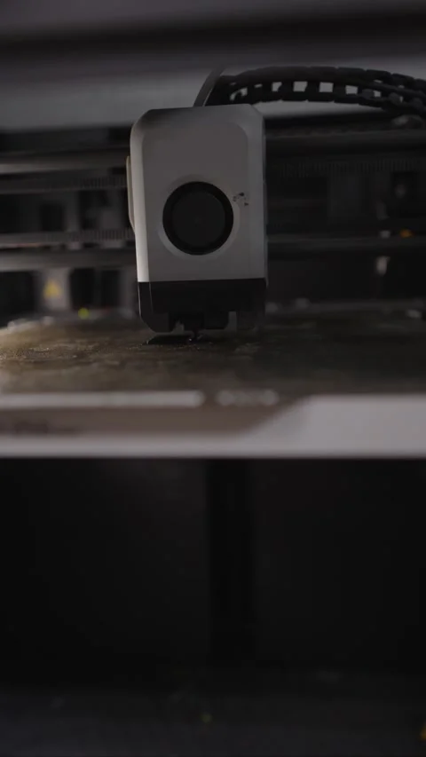 Close up view of a 3d printer head moving over the build plate, extruding Stock Footage 328988063