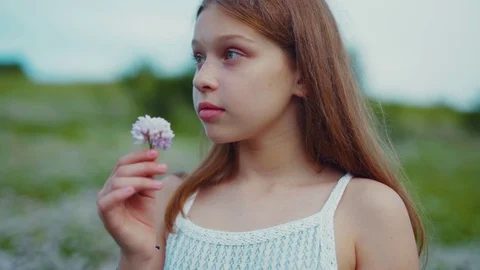 Close up view of adorable charming long-haired blue-eyed teenage girl smelling Stock Footage 113045213