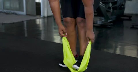 Close view of African American plus size woman stepping on resistance band and Vidéo 337647515