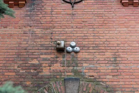 Close-up view of aged red brick facade displaying old security alarm box with Stock Photos