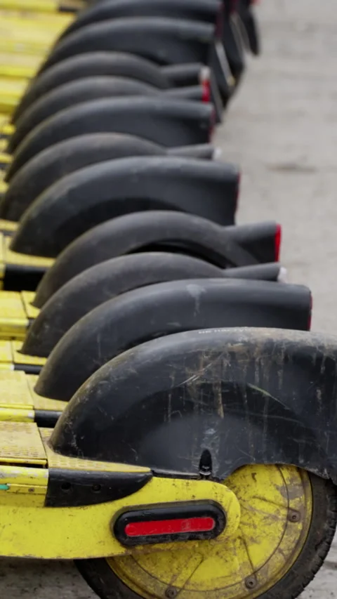 Close-up view of aligned electric scooters with muddy rear wheels, black fenders Stock Footage 317559593