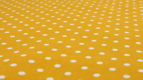 Close-up view of the amber yellow with white polka dots cotton fabric rotated Stock Footage 293885601