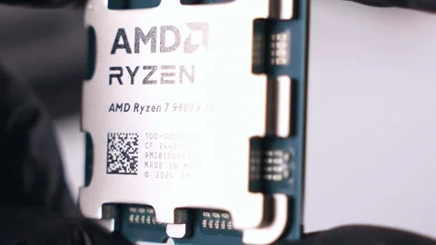 Close-up view of AMD Ryzen 7 9800X3D processor held in black gloves Stock Footage 294796543