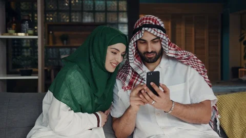 Close up view of arabic young couple sitting on a couch, bearded man in Stock Footage 107164394