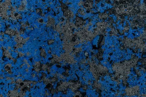 Close-up view of asphalt surface with stones covered with blue paint spots. Stock Photos