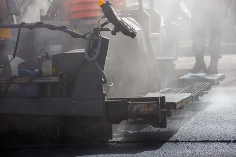 Close-up view of asphalting paver machine during road street repairing works at Stock Photos