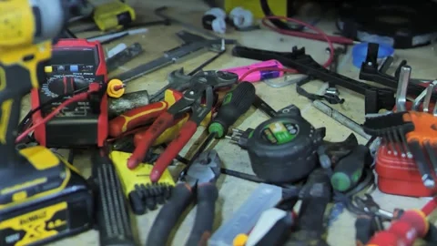 Close View of Assorted Hand Tools and Multimeter Scattered Across Workshop Bench Stock Footage 342781048