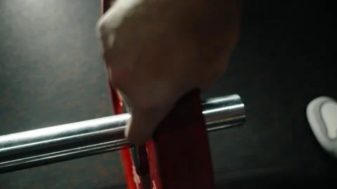 Close-up view of an athletes hand sliding a red weight plate onto a chrome 库存影片 329557400
