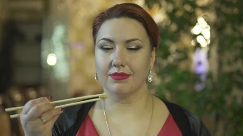 Close up view of attractive middle aged brunet woman eating food with chopsticks Stock Footage 137537350