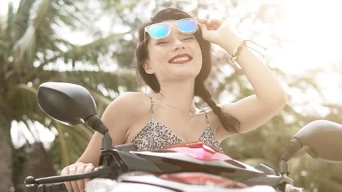 A close-up view of an attractive smiling asian woman is putting on a helmet and Stock Footage 250115596