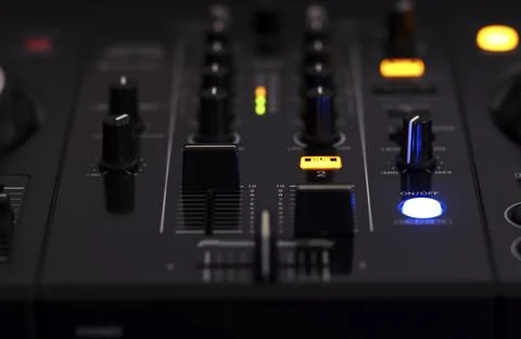 A close-up view of an audio mixer with various knobs, buttons, and glowing Stock Photos