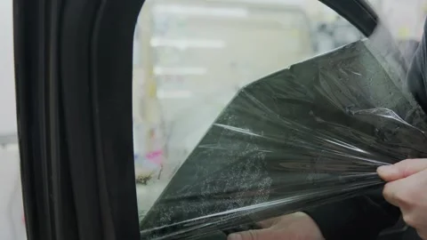 Close-up view of an auto detailer meticulously removing a dark, protective tint 스톡 동영상 337537899