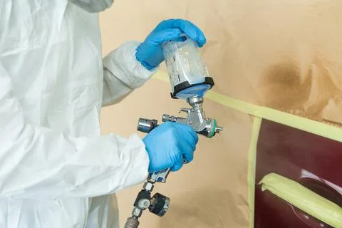 Close up view of auto painter in a protective suit and mask sprays 스톡 사진