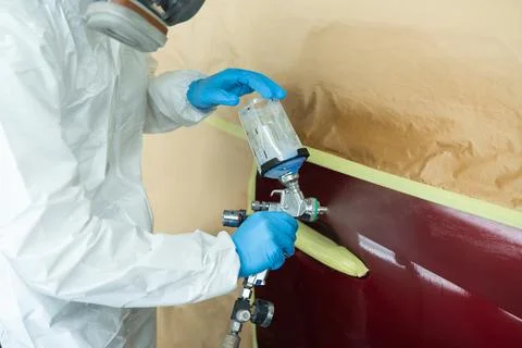 Close up view of auto painter in a protective suit and mask sprays 스톡 사진