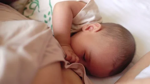 Close up view of Baby fall asleep holding mom on bed Stock Footage 201311576