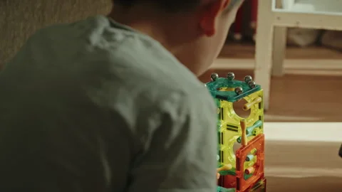 Close-up view from back of a boy playing with a magnetic constructor on a floor Stock Footage 255527207