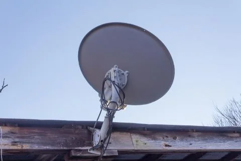 Close view of back of satellite dish on side of a barn Foto stock
