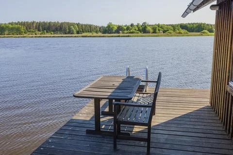 Close up view of backyard of patio located on lake with wooden table and bench. Stock Photos