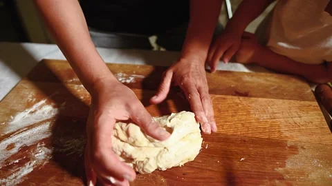 Close up view of baker and kid hands kneading dough on a wooden kitchen board. V Video stock 156410534