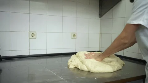 Close view of baker cleaning his hands and manually kneading bread dough bef 스톡 동영상 251370729