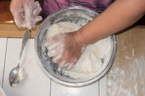 Close up view of baker kneading dough. Hands preparing dough in metal cup. Stock Photos
