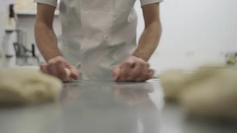 Close-up view of baker shaping dough pieces into bread rolls Stock Footage 251364243