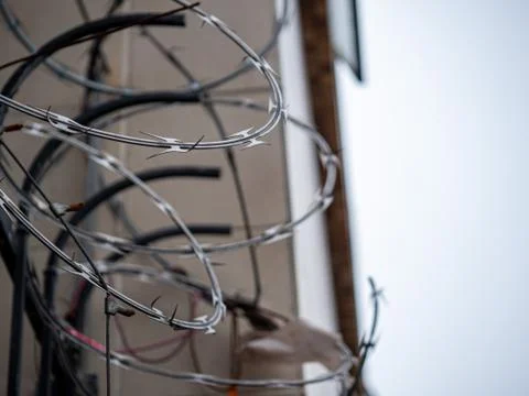 Close view of barbed wire razor wire on top of fence outside of a building in Stock Photos