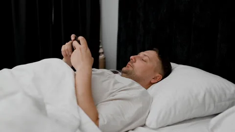 Close up view of bare male feet peaking out from under a soft white blanket or d Stock Footage 340144403