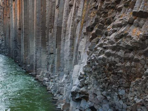 Close-Up View of Basalt Column Formation Next to a Calm Green River in Iceland Stock Photos