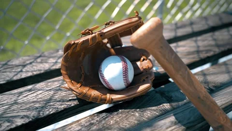 Close-Up View of Baseball Equipment on A Bench Next To A Grassy Baseball Field Stockbeeldmateriaal 202231054