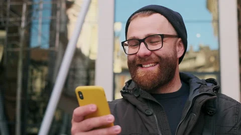 Close up view of bearded man in 30s looking at phone screen and laughing while Video stock 142136238