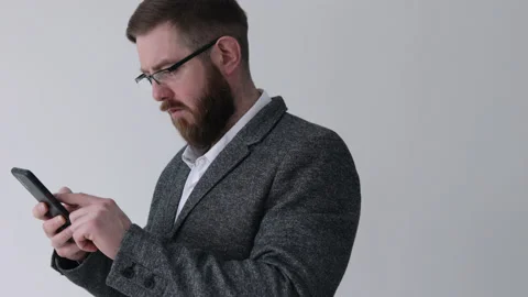 Close up view of bearded middle aged man using phone on the white wall Stock Footage 180396944
