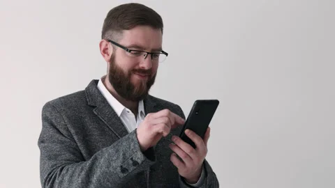 Close up view of bearded middle aged man using phone on the white wall Stock Footage 180397172
