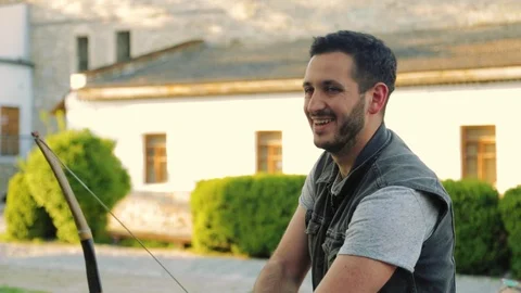 Close up view of bearded smiling unprofessional archer shooting with his bow Video stock 108726967