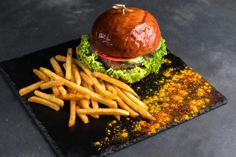 Close-up view on Beef burger with fresh vegetables and cheese served on a bla Stock Photos