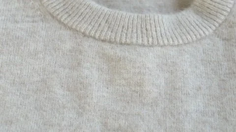 Close view of beige woolen or cashmere sweater collar showing knit structure and Stock Footage 332875821