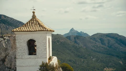 Close view of bell tower on cliff with mountain landscape background 스톡 동영상 333776604