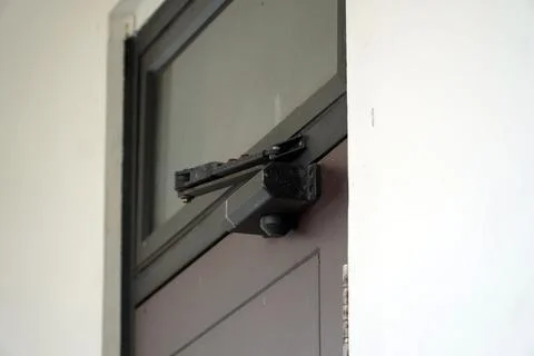 Close up view of a black automatic hydraulic door closer hardware installed  Stock Photos