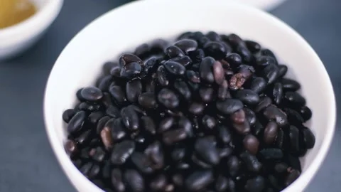 Close up view black beans in the white bowl. Healthy ingredients. Cooking Stock Footage 135236538