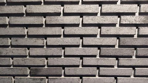 A close up view of a black brick wall with light Stock Photos