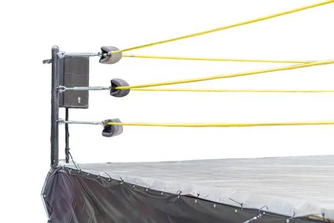 Close-up view of a black canvas boxing ring with yellow trim, turnbuckles, an Stock Photos